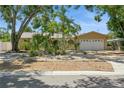 Exterior of a well maintained tan single-story home with a landscaped front yard and mature trees at 8020 28Th N Ave, St Petersburg, FL 33710