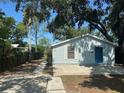 Inviting home with a blue front door, light blue siding and mature trees at 8618 N Orangeview Ave, Tampa, FL 33617
