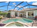 Screened-in pool and spa area with outdoor seating, brick patio, and lush landscaping for a relaxing backyard retreat at 8708 Laurel N Dr, Pinellas Park, FL 33782