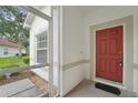 Inviting front door of a home with a vibrant red color and convenient screen door at 10263 Devonshire Lake Dr, Tampa, FL 33647
