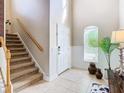 Bright foyer featuring tile flooring, a staircase with a wood banister, and a decorative rug at the front door at 10713 Shady Preserve Dr, Riverview, FL 33579