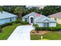 Charming single-story home featuring lush landscaping, a long driveway, and an American flag at 2121 Worthington Greens Dr, Sun City Center, FL 33573