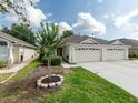 Inviting single-story home featuring a two-car garage, lush lawn, and mature landscaping at 31201 Shaker Cir, Wesley Chapel, FL 33543