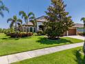 Attractive home featuring mature trees, a green lawn, and manicured shrubbery at 347 Cockle Shell Loop, Apollo Beach, FL 33572