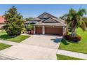 Well-maintained house featuring a spacious driveway, lush lawn, and mature palm trees at 347 Cockle Shell Loop, Apollo Beach, FL 33572