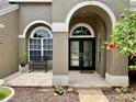 Welcoming front entrance with seating, lush gardens, decorative trim, and double glass doors at 4808 Jewell Ter, Palm Harbor, FL 34685