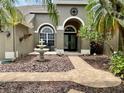 Charming home entrance with a brick walkway, fountain, lush plants, and a decorative front door at 4808 Jewell Ter, Palm Harbor, FL 34685