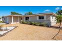 Well-maintained single-story home with light gray paint, rock landscaping, and mature bushes at 4842 Odyssey Ave, Holiday, FL 34690
