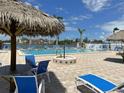 Outdoor pool area showcasing blue lounge chairs and tiki hut in a fenced in community at 5220 Brittany S Dr # 1306, St Petersburg, FL 33715