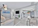 Bright, open-concept living room with modern furniture, stainless steel appliances, and light-colored wood floors at 10664 Starkey Rd, Seminole, FL 33777