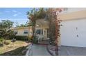 Charming single-story home's entrance with a flowering pergola, landscaping, and walkway at 10912 N 61St St, Temple Terrace, FL 33617
