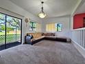 Bright living room featuring plush carpet, a large sectional couch, and sliding glass doors to the patio at 12701 N 57Th St, Tampa, FL 33617
