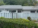 A quaint one story home with a white fence and green manicured bushes create a private and welcoming curb appeal at 1371 Pine Ridge E Cir # B8, Tarpon Springs, FL 34688