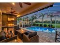 Inviting screened pool area with an outdoor kitchen, a built-in grill, a cozy seating area, and picturesque golf course views at 1617 El Pardo Dr, Trinity, FL 34655
