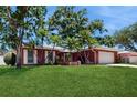 Well-maintained brick home featuring a green lawn, mature trees and manicured landscaping at 2138 Viola Dr, Clearwater, FL 33764