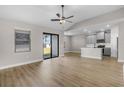Bright living room featuring wood floors, a ceiling fan, and a kitchen area with modern gray cabinets at 2426 Hiers Rd, Dover, FL 33527