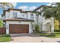 Elegant two-story home featuring a barrel tile roof, brick driveway, and manicured landscaping at 3404 W Sevilla St, Tampa, FL 33629