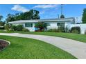 Well-manicured front yard with lush lawn and a blue door single-story home at 3701 Manatee Se Dr, St Petersburg, FL 33705