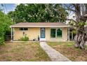 Inviting single-story home boasts a walkway, blue front door, well-maintained landscaping, and carport at 4411 W Bay Villa Ave, Tampa, FL 33611