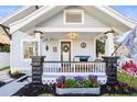 Inviting front porch featuring stone columns, flowers, and a cozy sitting area with decorative pillows at 634 6Th N St, St Petersburg, FL 33701