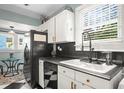 Bright kitchen with white cabinets, a black refrigerator, and black and white checkered flooring at 634 6Th N St, St Petersburg, FL 33701