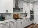 Well-appointed kitchen featuring white cabinets, a tile backsplash, and stainless steel appliances and fixtures at 718 W Kentucky Ave, Tampa, FL 33603