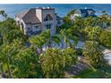 Beautiful exterior view highlighting lush tropical landscaping, a circular driveway, and a waterfront location at 812 Point Seaside Dr, Crystal Beach, FL 34681