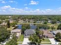Aerial view of houses in a tranquil neighborhood surrounding a serene pond with a water fountain at 9223 Brindlewood Dr, Odessa, FL 33556