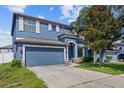 Two-story blue home with white shutters, arched entry and a two car garage, surrounded by mature trees at 10808 Whitecap Dr, Riverview, FL 33579