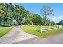 Scenic view of a home with a long driveway, white fence, and beautiful mature trees at 11109 Winn Rd, Riverview, FL 33569