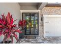 Stylish front entrance featuring a modern double door, brick accents, and vibrant plants at 13859 Sharp Hawk Dr, Riverview, FL 33569