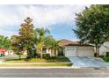 Attractive single-story home featuring mature trees, a well-manicured lawn, and an attached two-car garage at 14027 Bensbrook Dr, Spring Hill, FL 34609