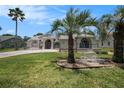 Landscaped front yard with palm trees and decorative elements creating a welcoming and attractive exterior at 14181 Cornewall Ln, Spring Hill, FL 34609