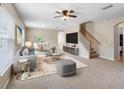Bright, staged living room featuring neutral carpet, ceiling fan, and an open floor plan at 18320 Snowdonia Dr, Land O Lakes, FL 34638
