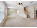 Spacious living room featuring neutral carpet, ceiling fan, and stairs to the upper level at 18320 Snowdonia Dr, Land O Lakes, FL 34638