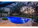 A gorgeous screened in pool and patio, with blue accent lighting and outdoor dining furniture in the backyard at 2048 Douglas Ave, Dunedin, FL 34698