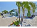 View of the home exterior with a well manicured lawn, pavers, tropical landscaping, and a white picket fence at 214 Lookout Dr, Apollo Beach, FL 33572