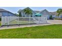 Charming home with a white picket fence, lush lawn, tropical palm, and welcoming outdoor seating area at 214 Lookout Dr, Apollo Beach, FL 33572
