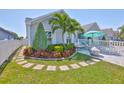 Well-manicured front yard featuring a palm tree, shrubs, colorful flower bed, and stepping stone pathway at 214 Lookout Dr, Apollo Beach, FL 33572