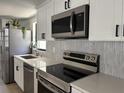 Close up of kitchen featuring stainless steel appliances, white cabinets, and grey subway tile backsplash at 2551 12Th St, Englewood, FL 34224