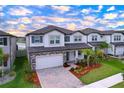 Beautiful two-story home with a two-car garage, manicured lawn, and colorful landscaping at 3063 Marine Grass Dr, Wimauma, FL 33598