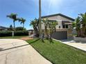 Stunning two-story home showcasing a stone facade, well-manicured lawn, and tropical landscaping in a sunny setting at 3654 Corsair Ct, New Port Richey, FL 34652