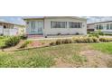 This home's curb appeal includes green shutters, well-maintained lawn, and a charming entrance with lovely plants at 36750 Beth Ave, Zephyrhills, FL 33542