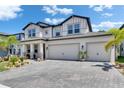 Charming two-story home featuring a three-car garage and brick paver driveway under a blue sky at 5026 Bromeliad Ave, Wimauma, FL 33598