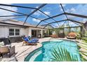 A screened-in pool area featuring lounge chairs, hot tub, a dining table and an outdoor bed at 5026 Bromeliad Ave, Wimauma, FL 33598