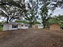 Charming house and detached garage with a metal roof surrounded by mature shade trees at 5535 Peach Ave, Seffner, FL 33584