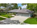 View of exterior features of home and two car garage with an expansive driveway and large lawn at 1014 Sylvia Ln, Tampa, FL 33613