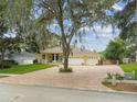 Charming single-story home with a three-car garage, landscaped yard, and long brick driveway at 10306 Shalimar Wood Dr, Thonotosassa, FL 33592