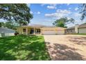 Charming single-story home with a three-car garage, landscaped yard, and inviting front porch at 10306 Shalimar Wood Dr, Thonotosassa, FL 33592