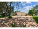 Charming single-story home with a three-car garage, landscaped yard, and long brick driveway at 10306 Shalimar Wood Dr, Thonotosassa, FL 33592
